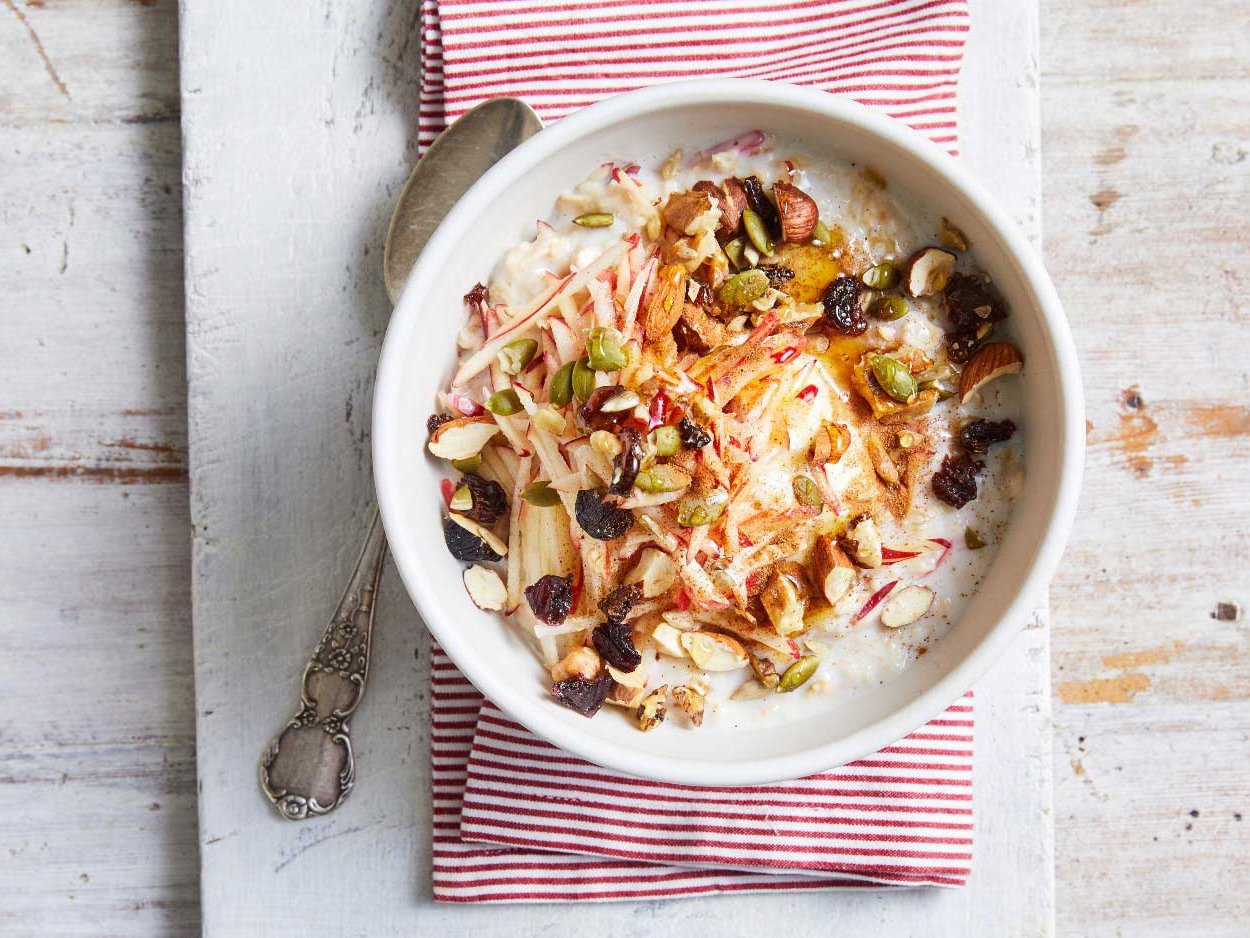 A bowl of oatmeal topped with nuts and raisins