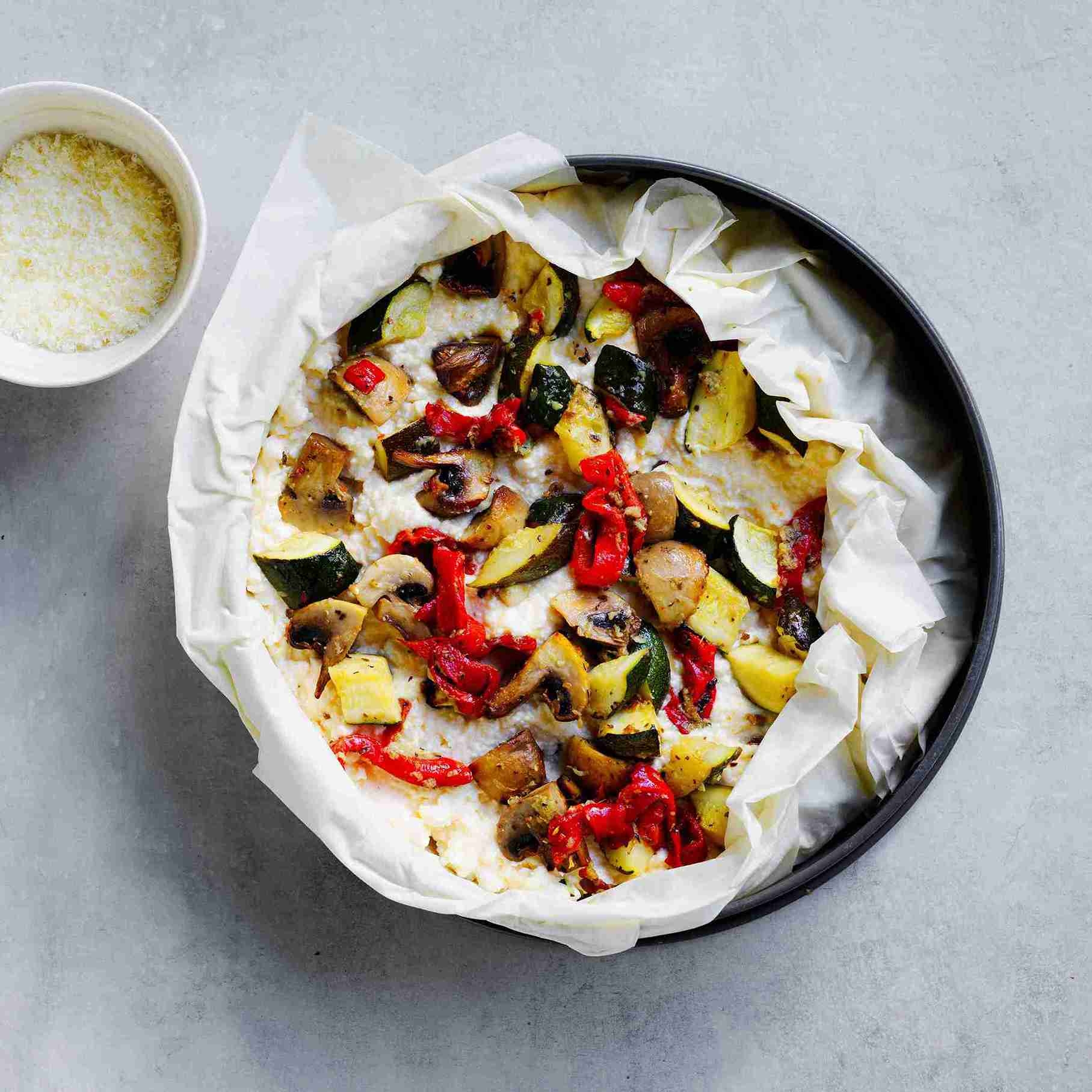 layering roasted vegetables and ricotta mixture into a pastry case, folding edges and topping with parmesan