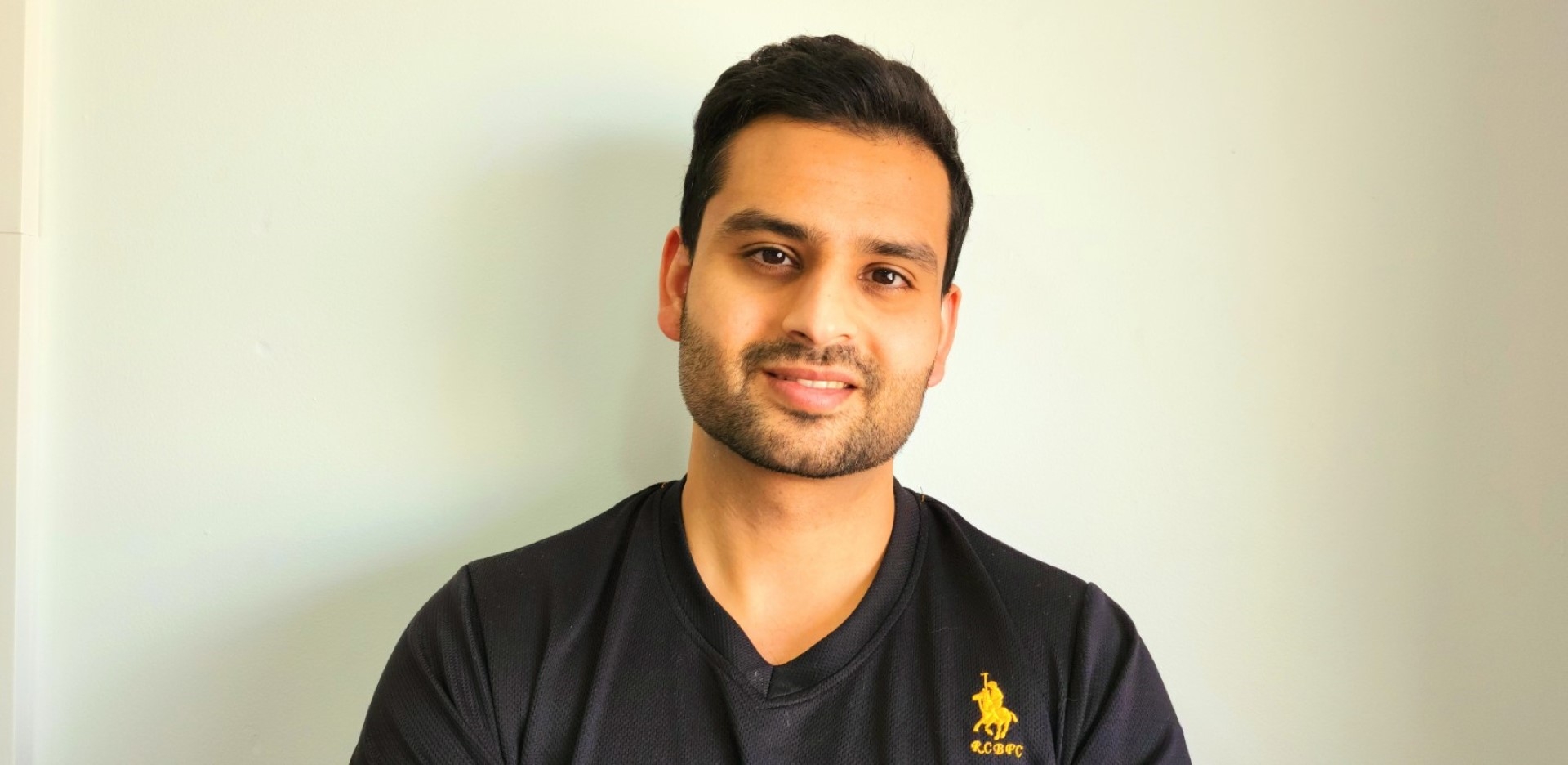 A headshot of Dr Umar Ali smiling in front of a white wall