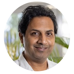 An Indian man in a white shirt smiling, radiating warmth and happiness.