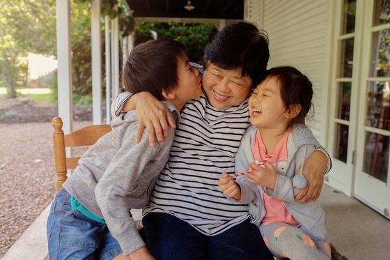 A woman, flanked by two young children, laughing and hugging
