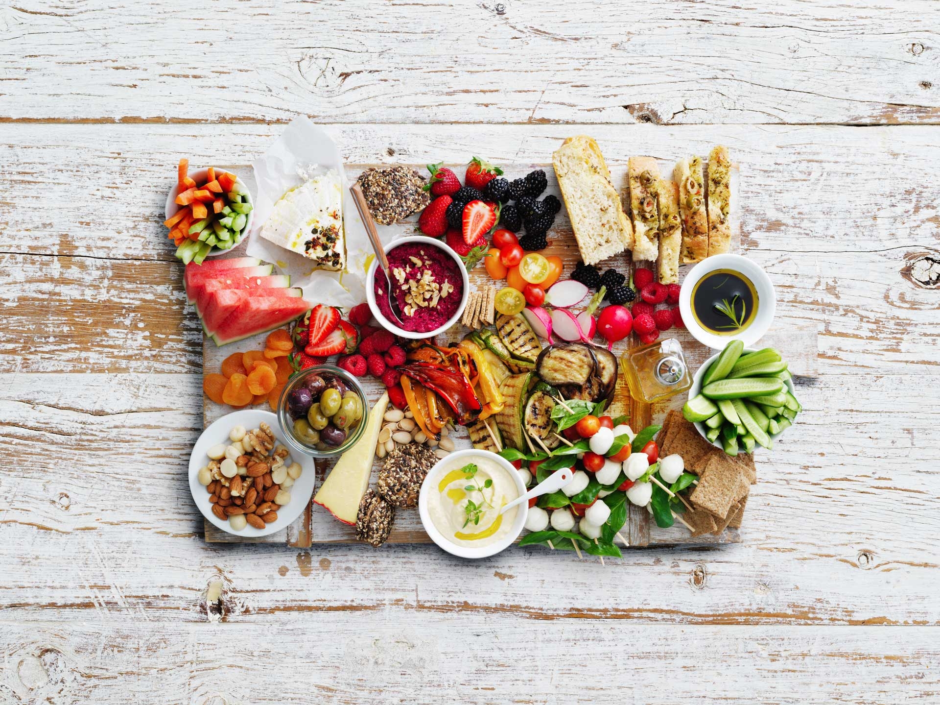 Grazing board filled with salad, fruit, nuts, breads and dips 