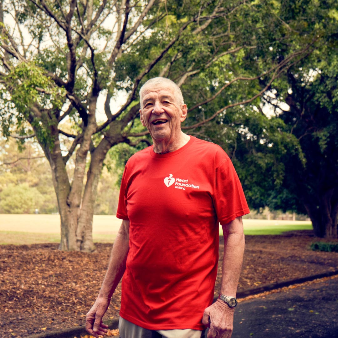 Smiling man in red t-shirt walking through a park