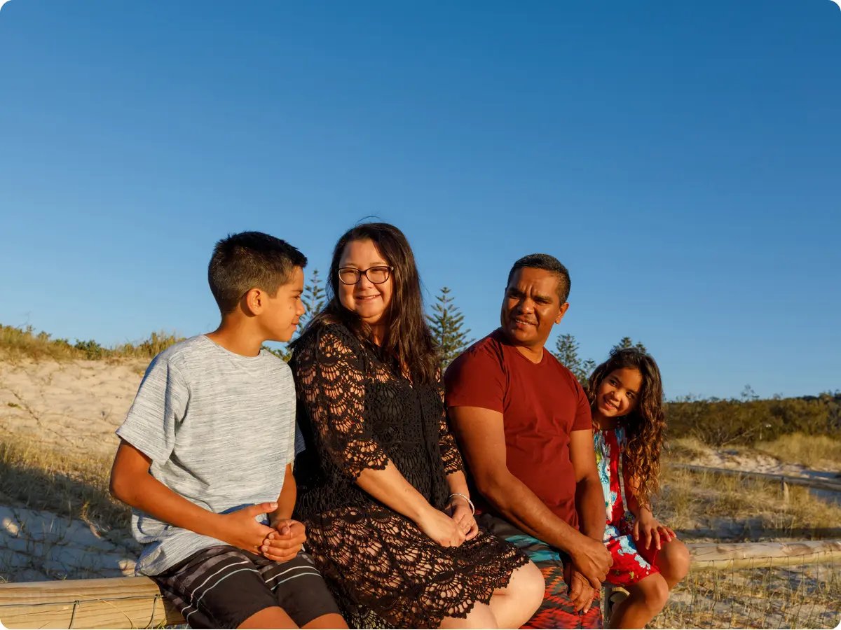 A happy family sitting on the sandy beach while the sun sets 