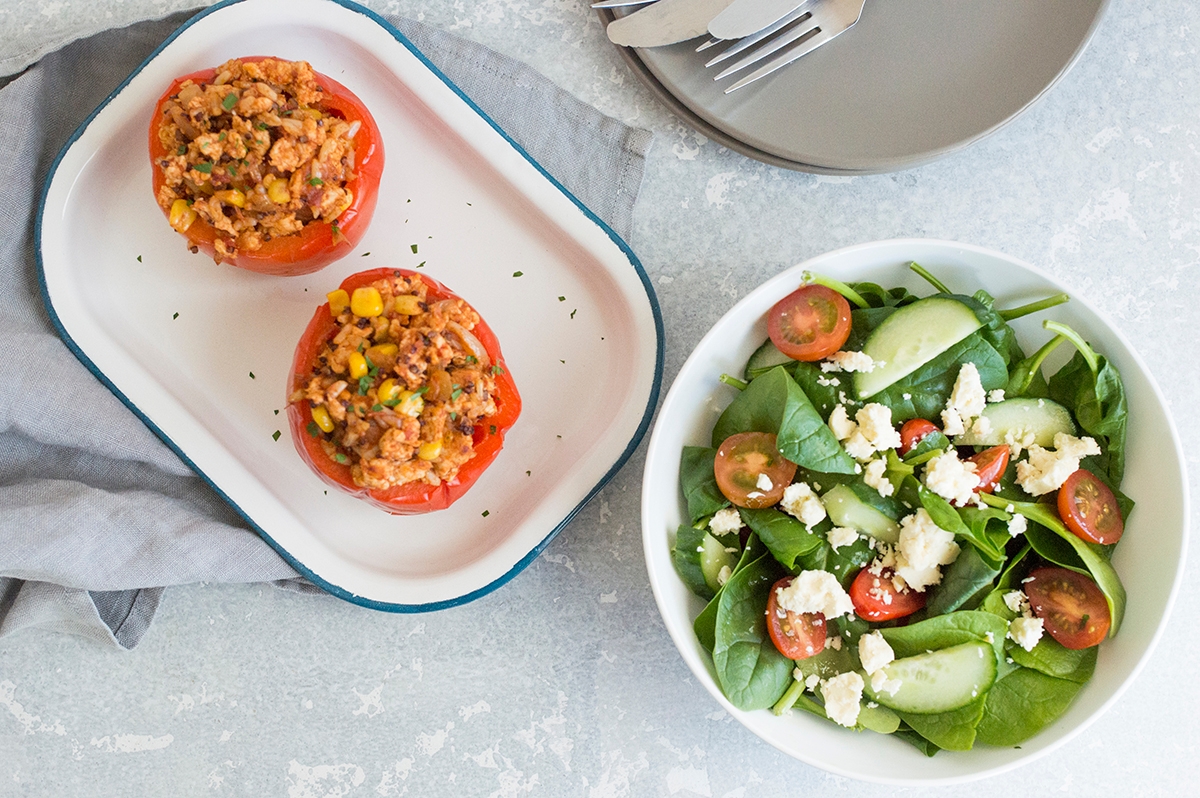 A plate with 2 stuffed peppers and a salad