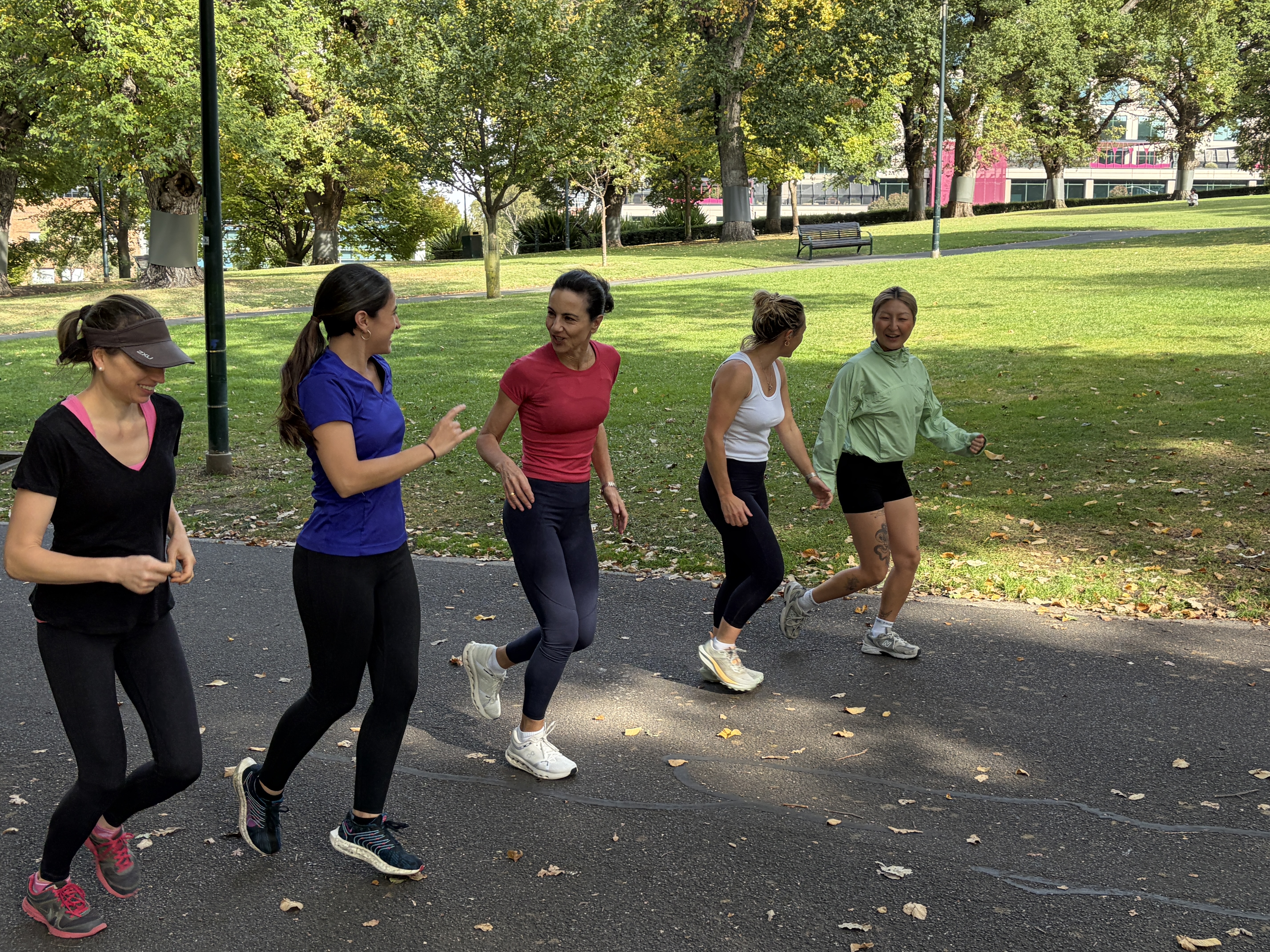 A group of people running in the park on a sunny day 