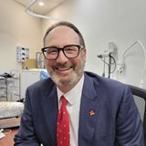 Grant Blashki in a suit and tie sitting at a desk, focused and engaged in his work.