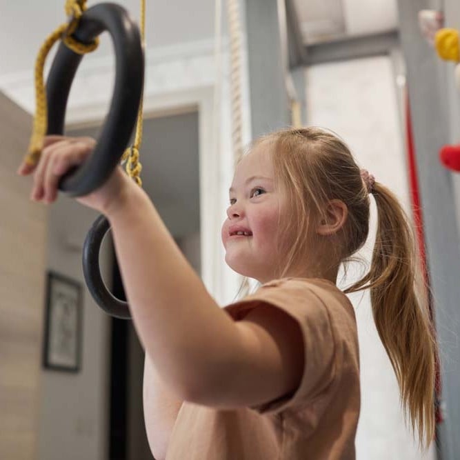 Child using gymnastic rings during an indoor physical activity session.