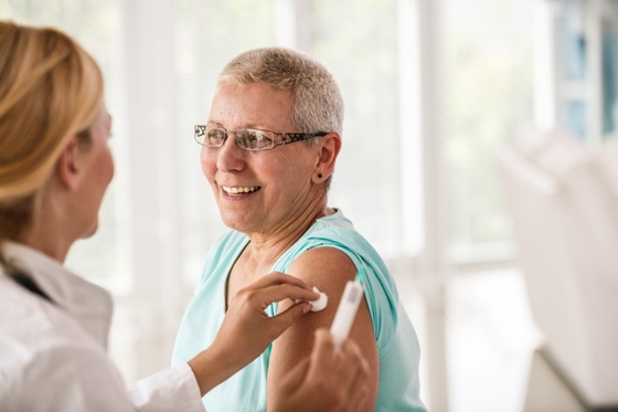 A woman receiving her COVID-19 and flu vaccination from her doctor.