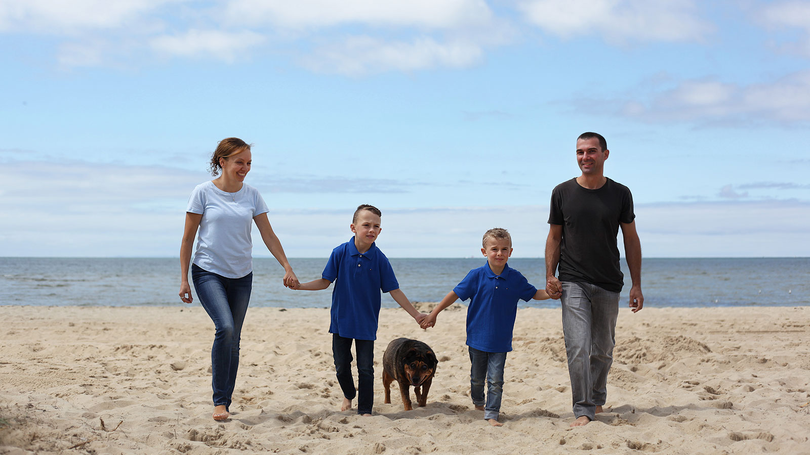 A family walking on the beach, holding hands, enjoying a peaceful and bonding moment together.
