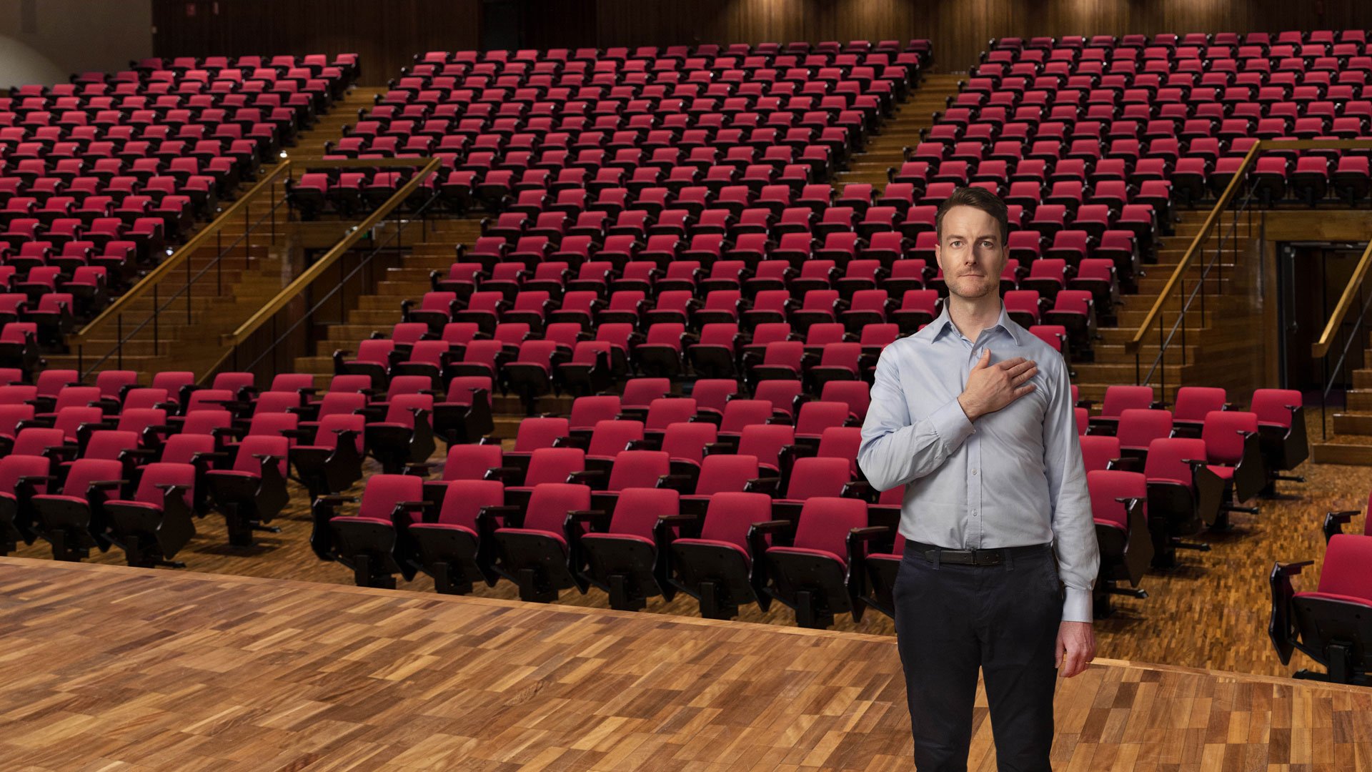 Geoff Lester with hand on heart, in a lecture theatre