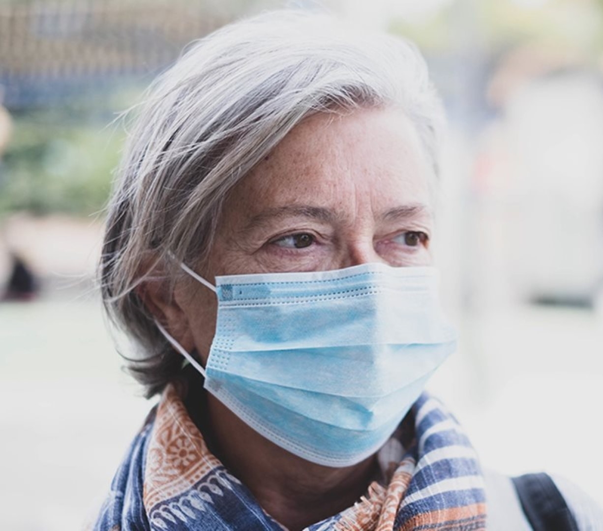 An elderly woman wearing a protective face mask to prevent the spread of germs.