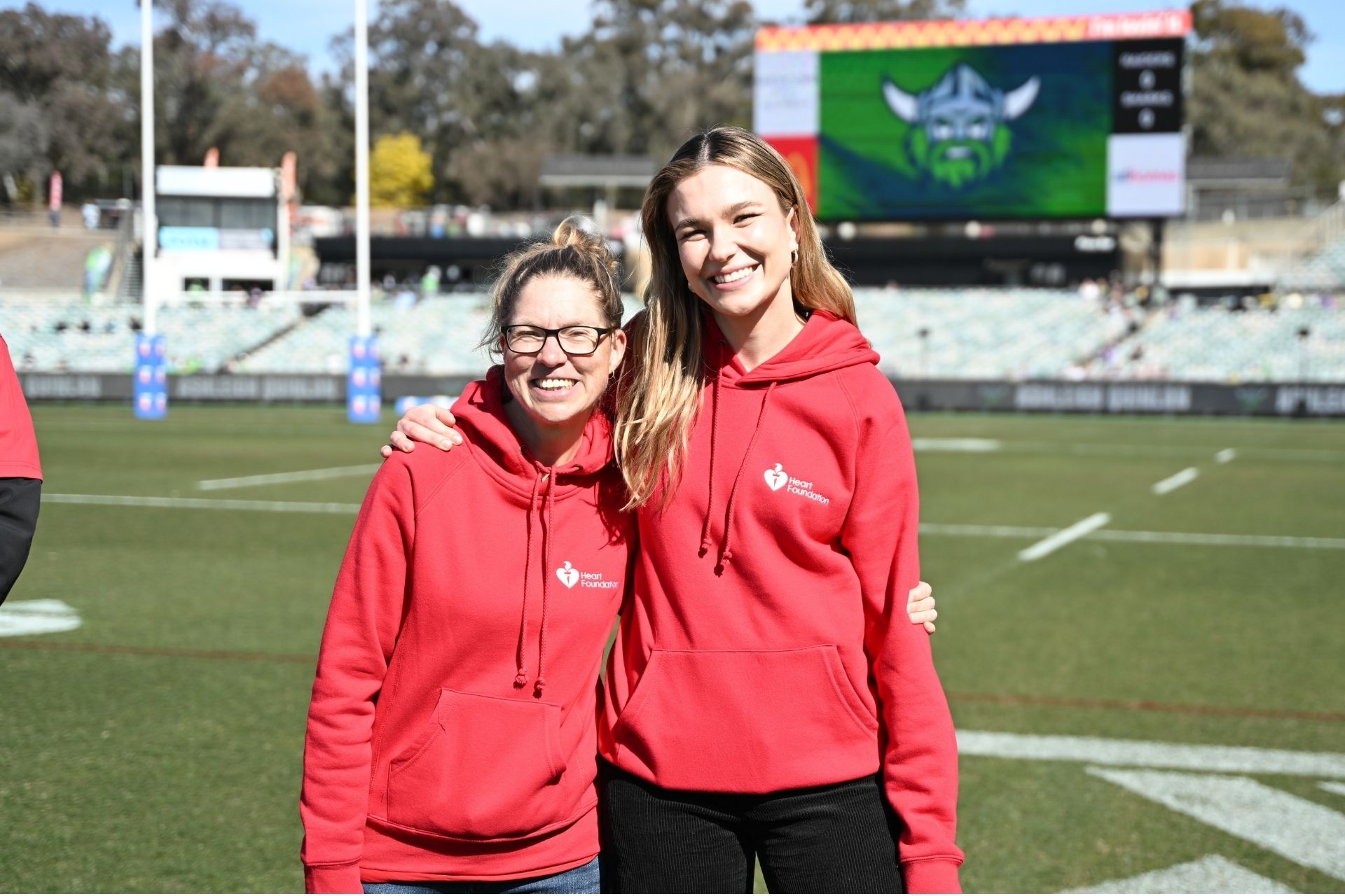 Two Heart Foundation staff standing on a rugby field during partnership event