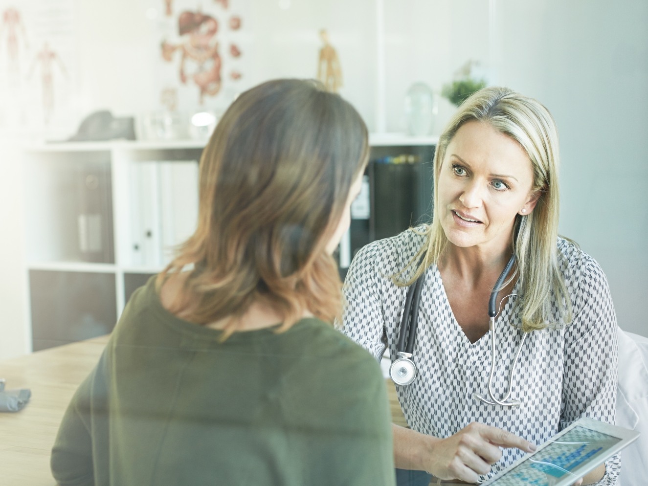 A woman discussing her health concerns with a doctor in a professional office setting.