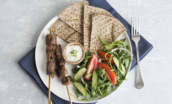 A plate with a delicious assortment of meat, vegetables, and pita bread