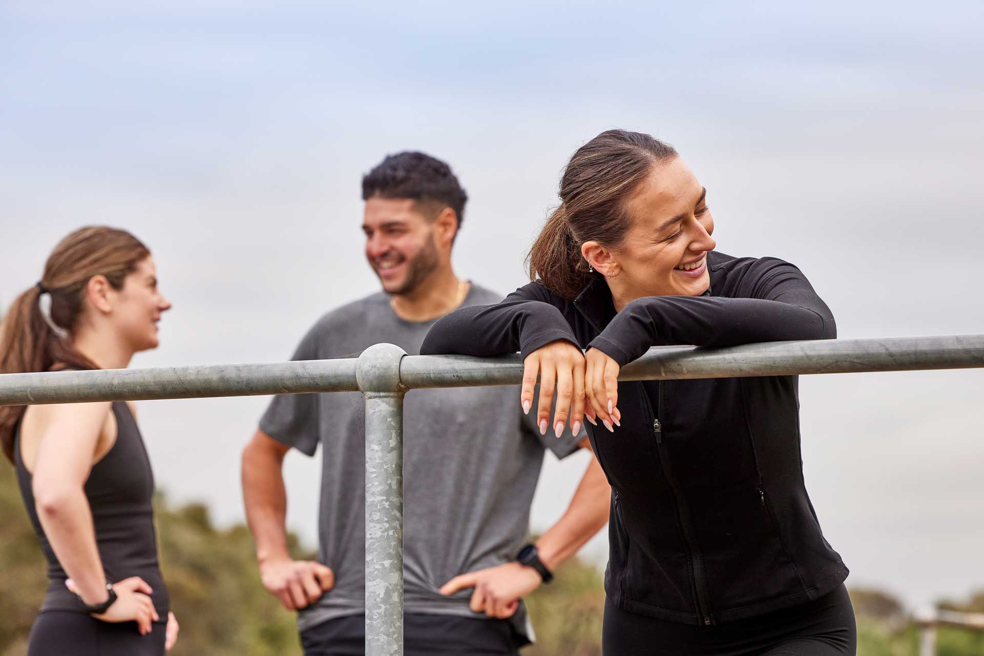 Three adults exercising outdoors smiling