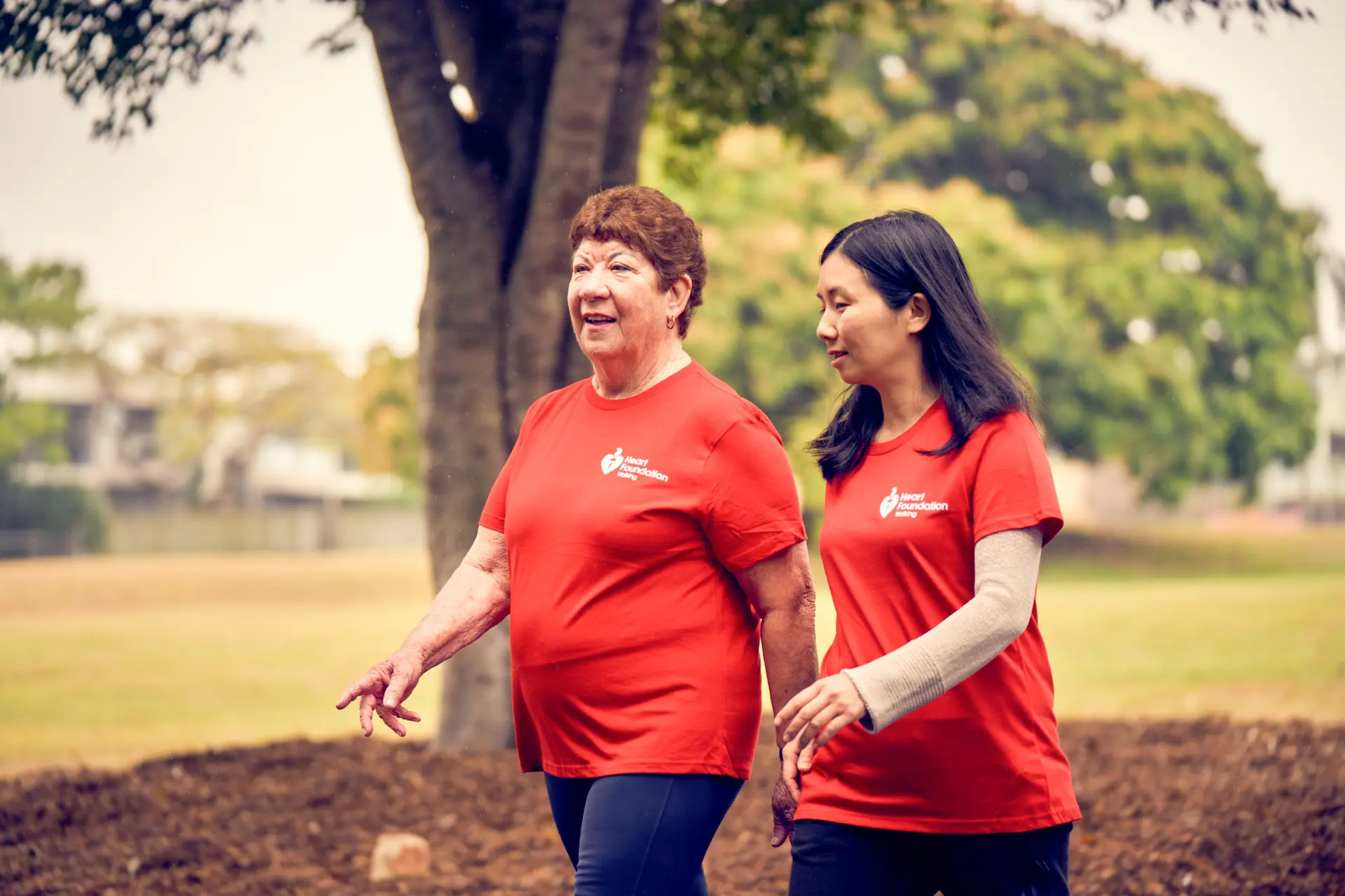 Two women wearing Heart Foundation shirts walking together outdoors