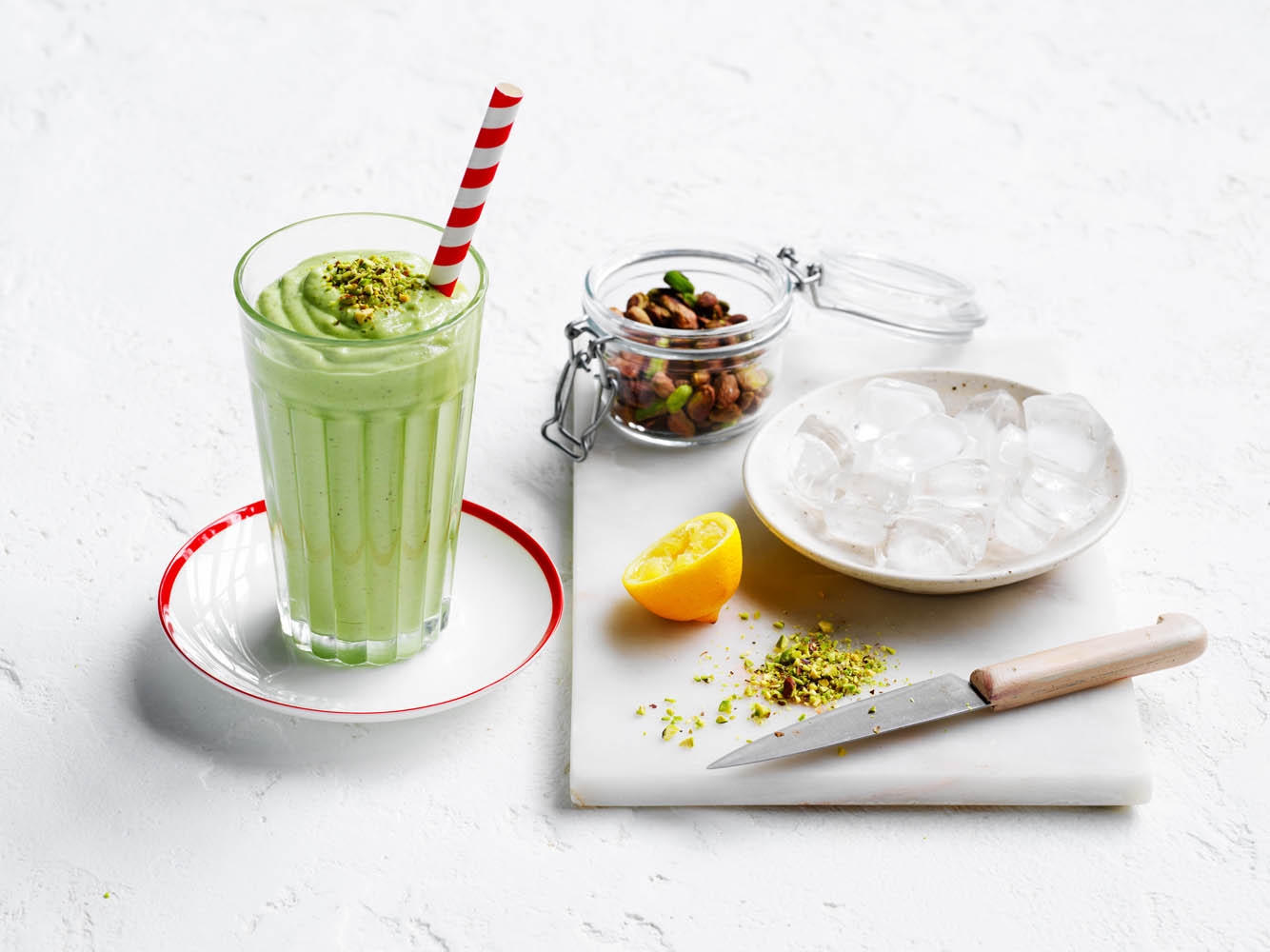 Pistachio smoothie serves in a glass with colourful setting
