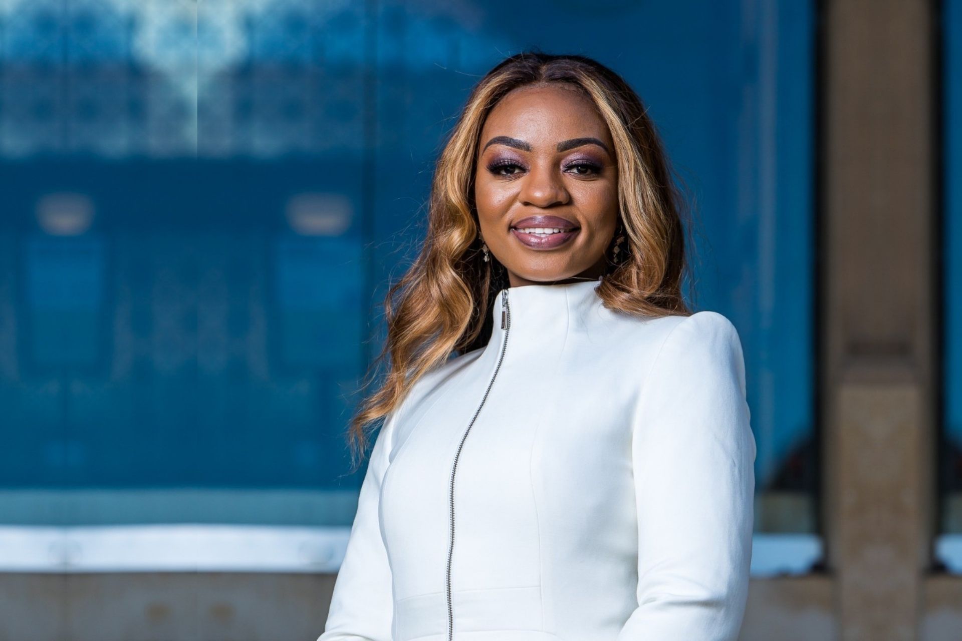 A headshot for Jocelyne Mulangala, a smiling black woman wearing a white jacket