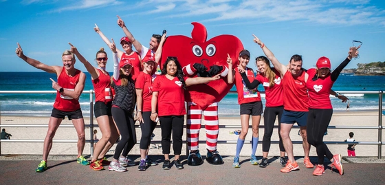 Group of Heart Foundation team in red shirts with a big red heart in front of a beach