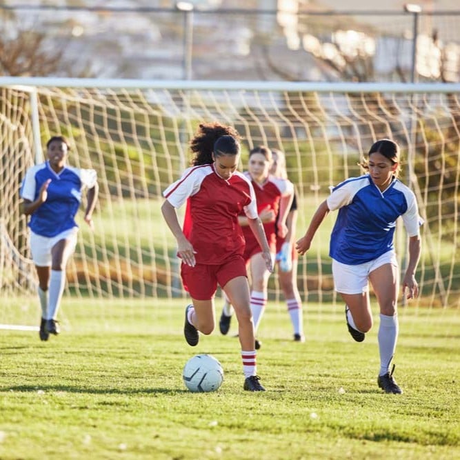People playing soccer on a community sports field in an urban park