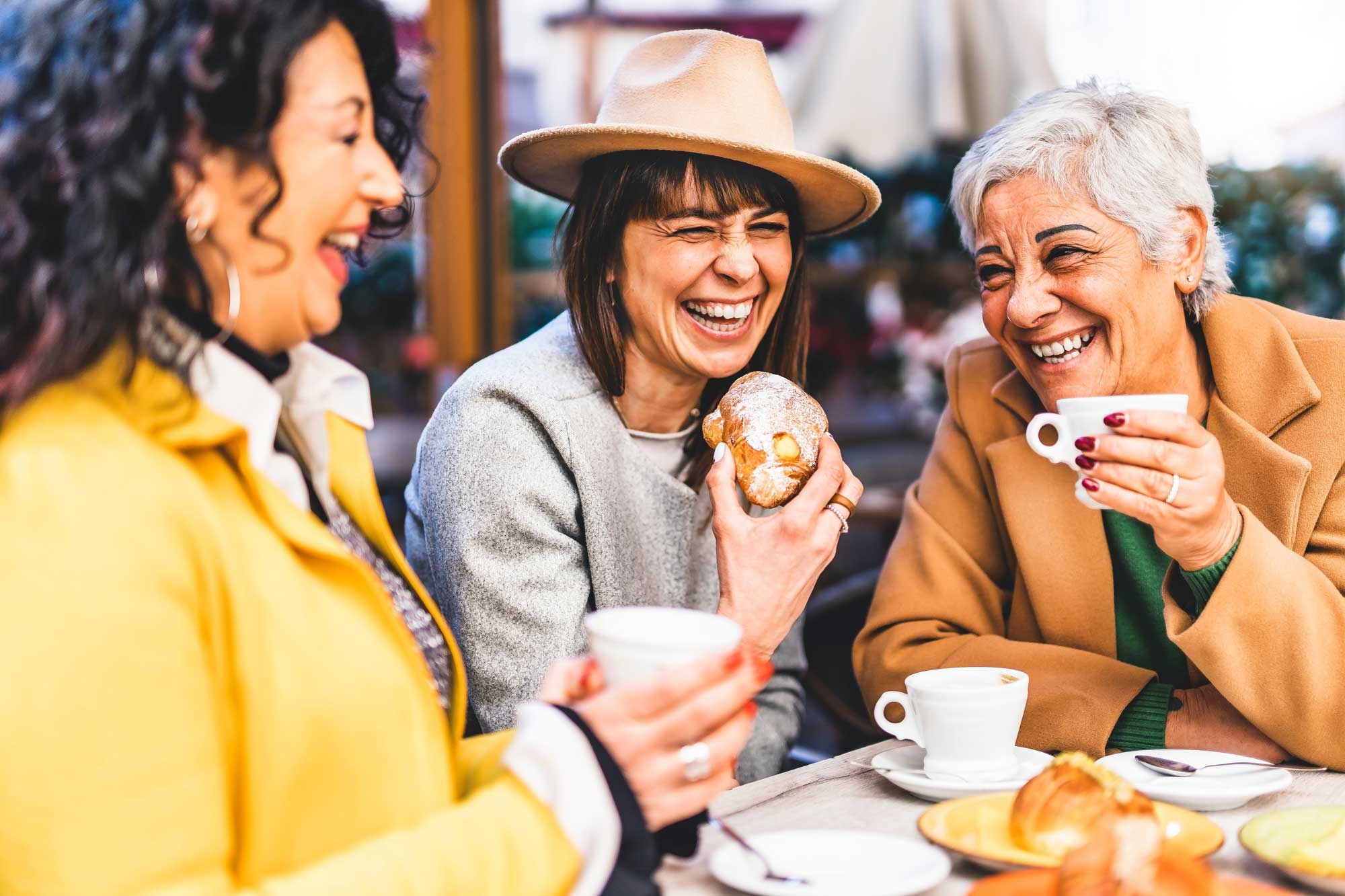 Three women getting together at a cafe, laughing and feeling good