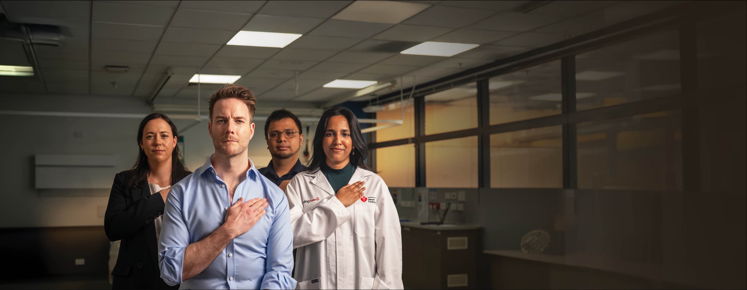 A group of Heart Foundation funded researchers standing in a lab with their hands over their hearts