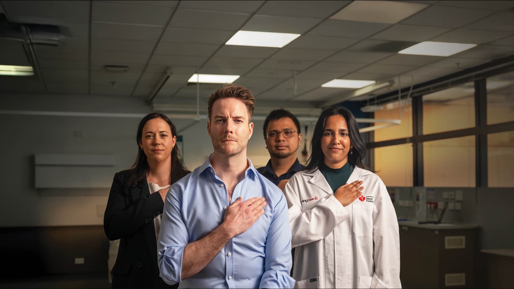 A group of Heart Foundation funded researchers standing in a lab with their hands over their hearts