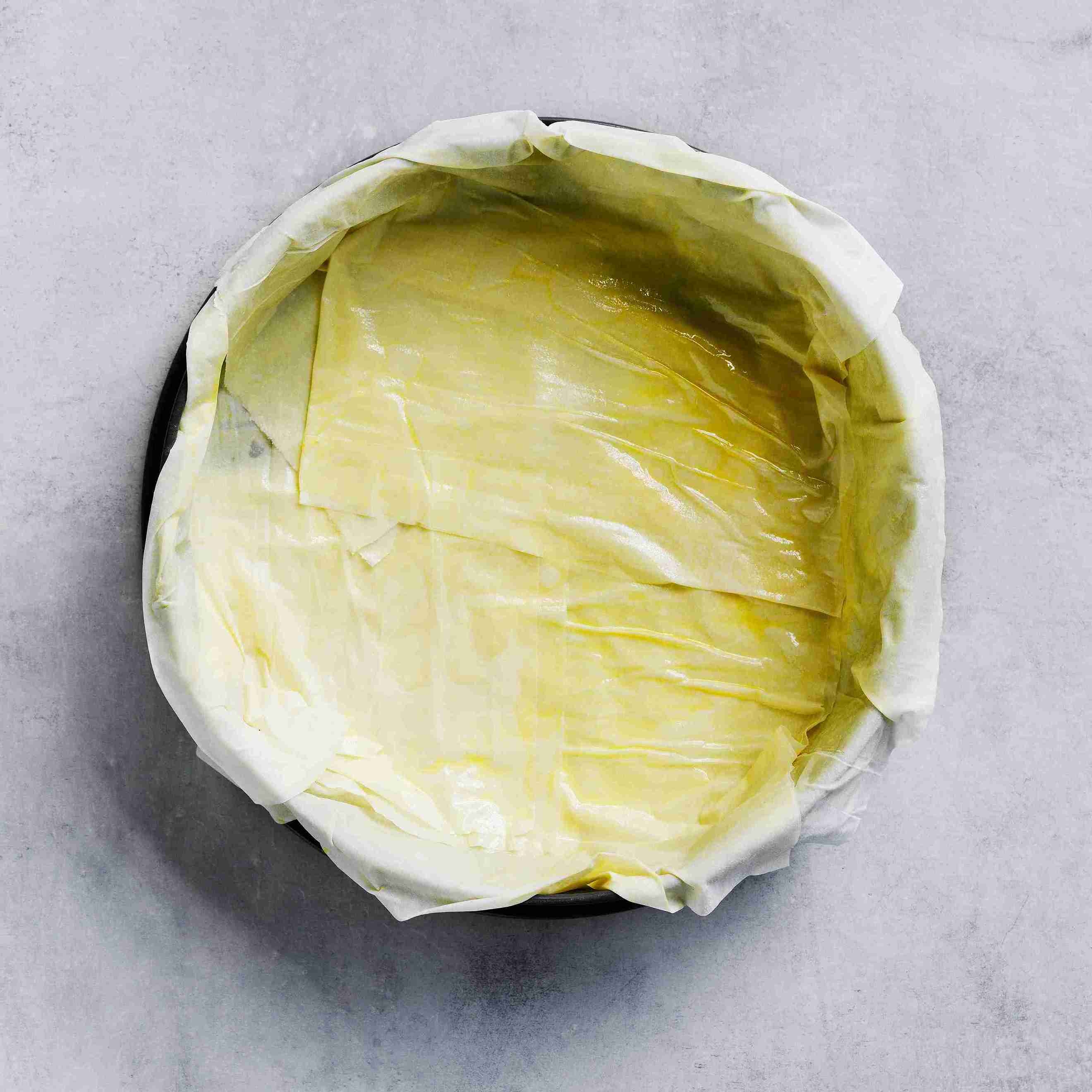 layering and spraying filo pastry sheets into a round springform pan