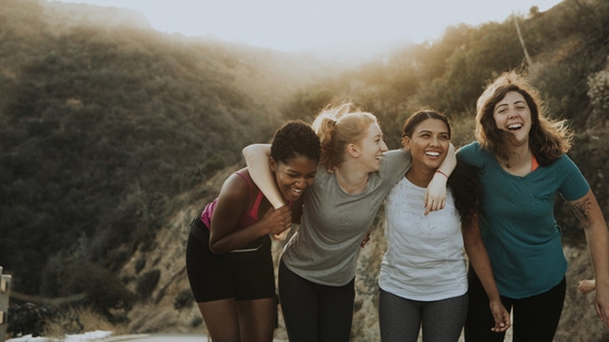 Four women smiling and laughing while out hiking