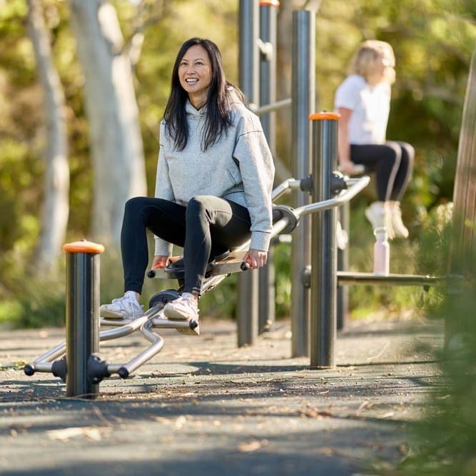 Person using outdoor fitness equipment in a public park.