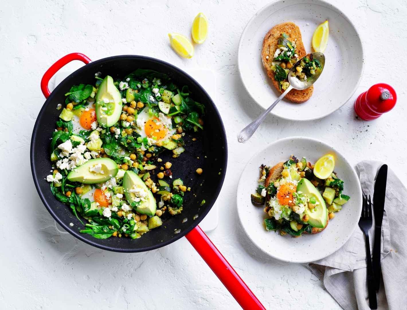 Green shakshuka completed dish served on a table with side dishes