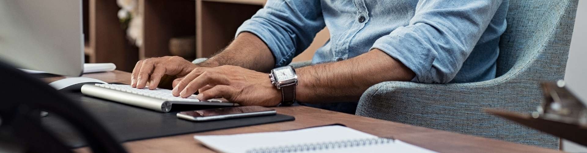 View of persons hands at desk typing on keyboard 