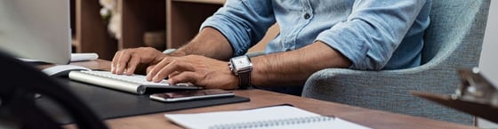 View of persons hands at desk typing on keyboard