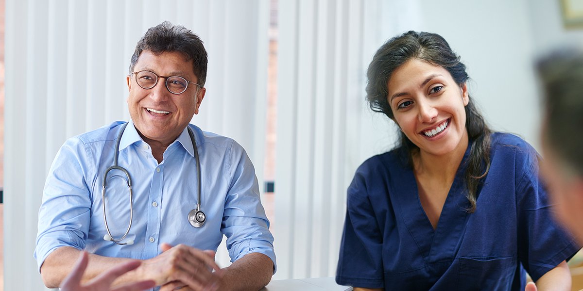 Male and female health professionals smiling sitting side by side