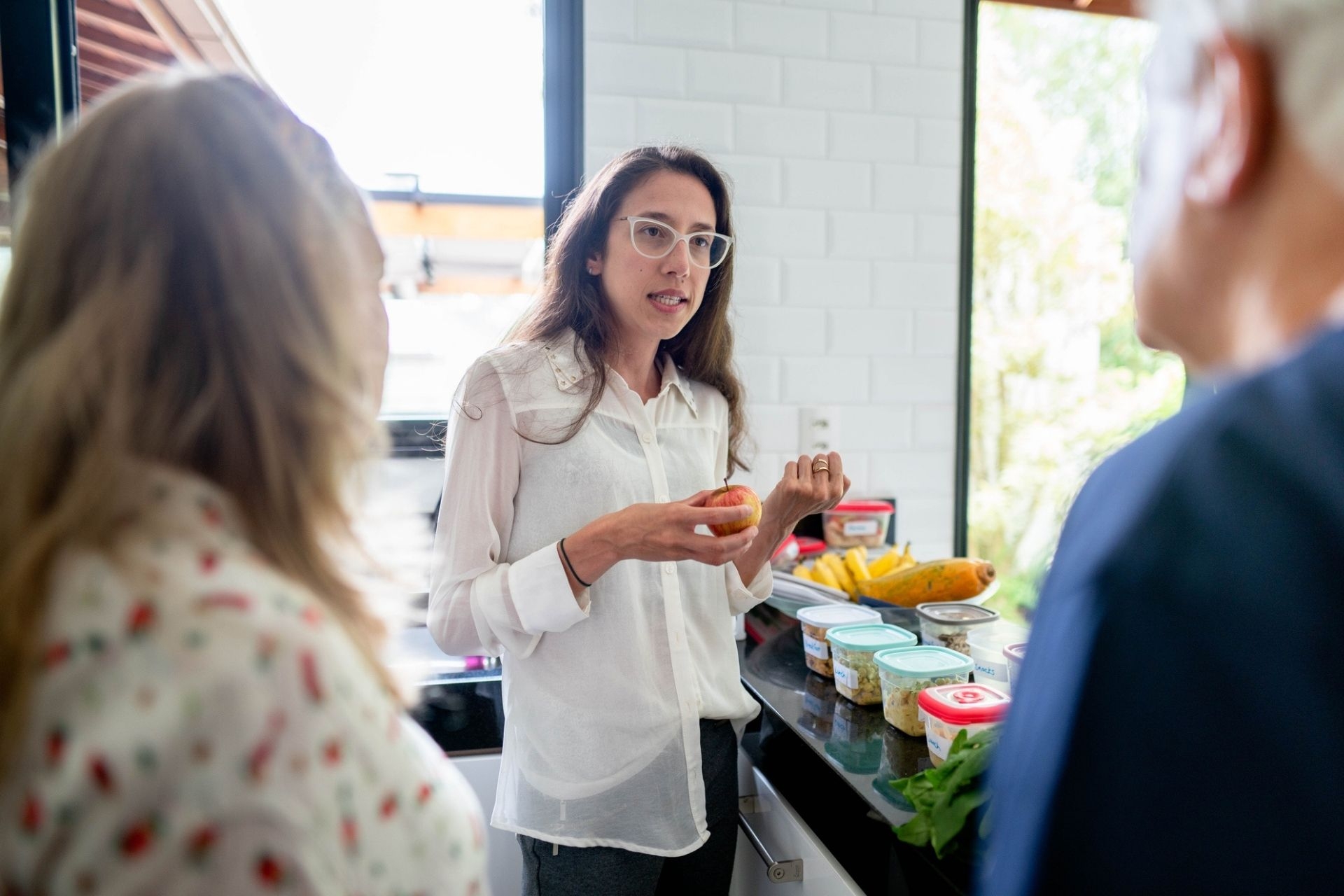 Young nutritionist discussing meal planning with a senior couple during a diet consultation in their kitchen at home