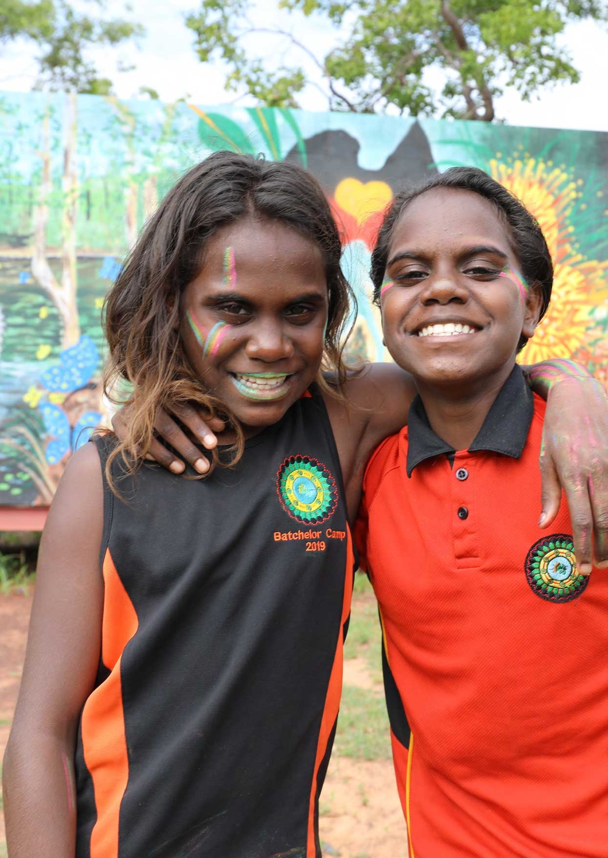 Two young Aboriginal girls standing next to each other, arms around