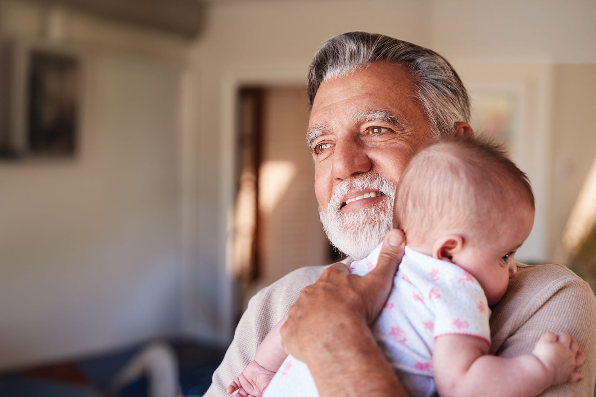 A older man with a white beard, holding a baby.