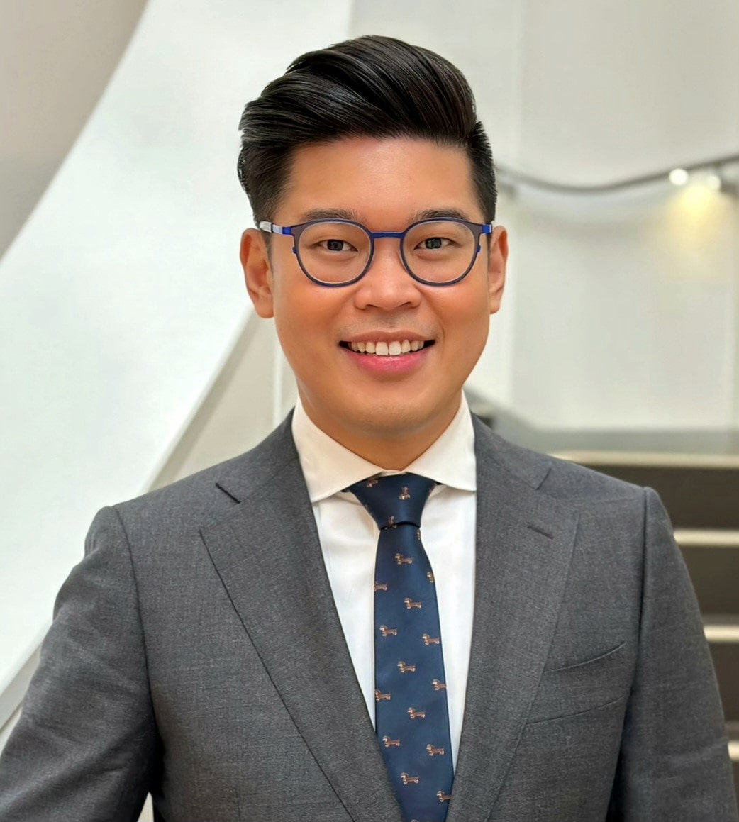 Dr Dion Candelaria standing and smiling in a suit
