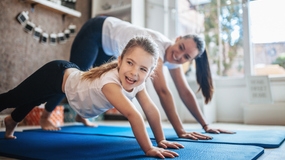 A mother and daughter practicing yoga together on a mat, enjoying and connecting