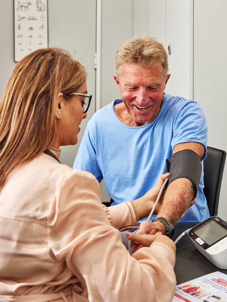 Mature man in blue t-shirt getting blood pressure taken by healthcare professional