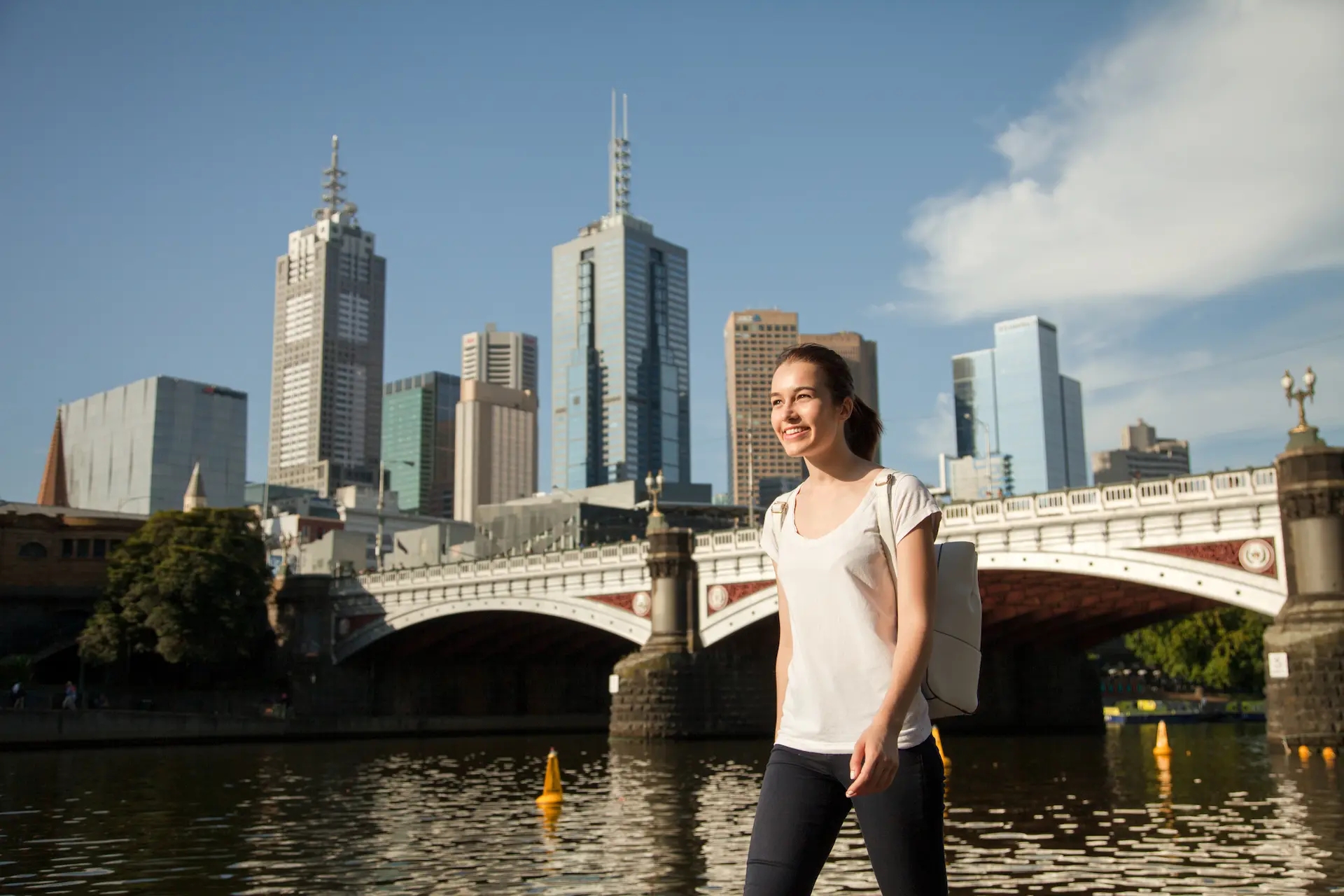 A young woman smiling and walking to work along river