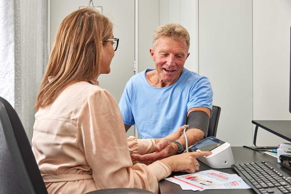 Mature man in blue t-shirt getting blood pressure taken by healthcare professional