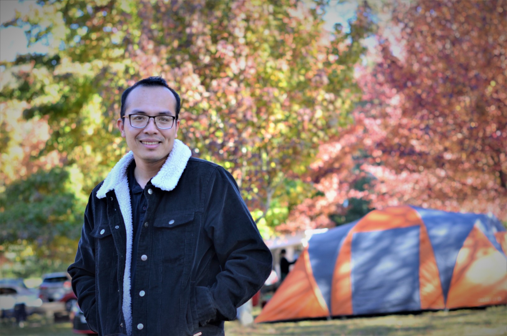 Dr Thanh Nho Do smiling in front of a green background of trees