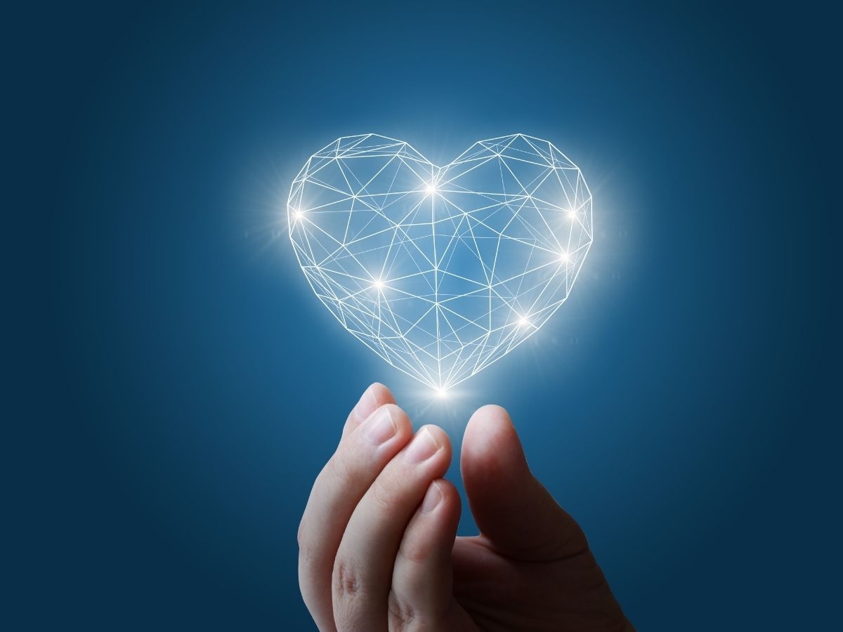 A hand holding a holographic heart with network graphics