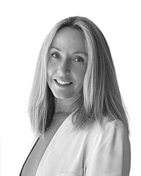 Katie Stewart wearing a white blazer poses for a black and white photo.