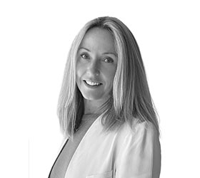 Katie Stewart wearing a white blazer poses for a black and white photo.
