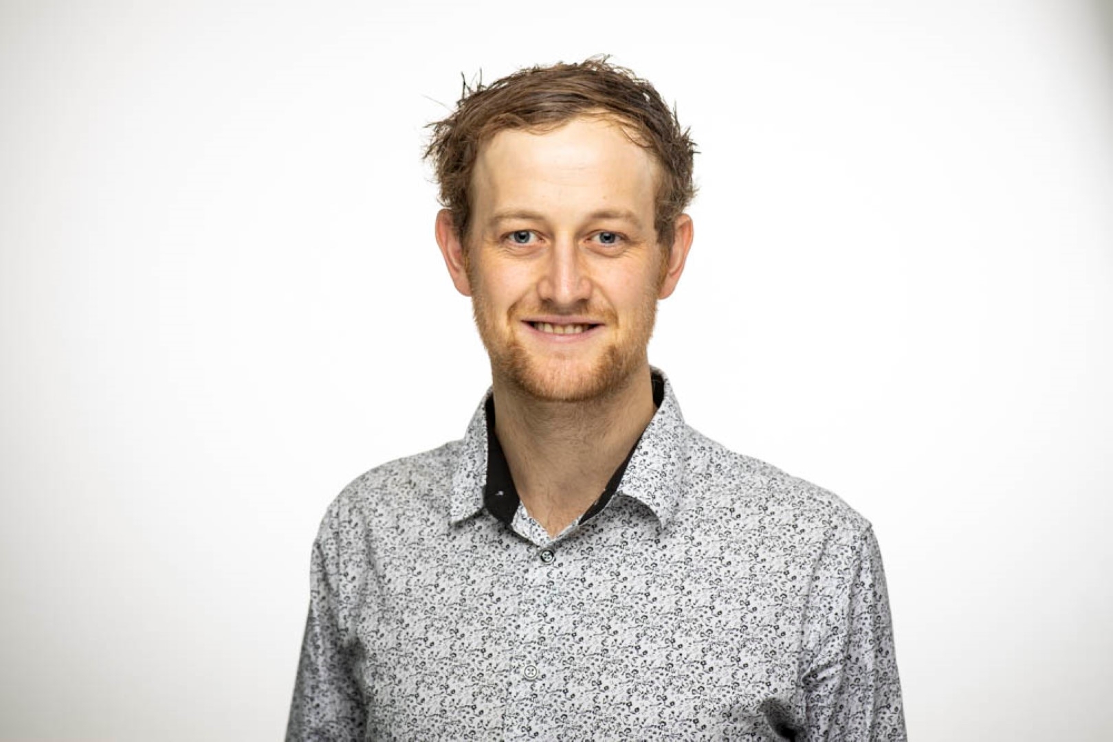 Jaimon Kelly smiling in front of a white background