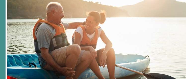 Two people sitting and laughing in lifevests sitting on a boat next to a lake