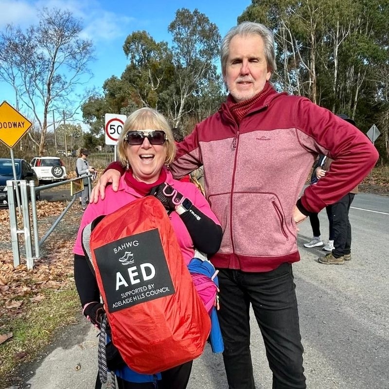 Walking group members, a man and a woman, holding a portable AED